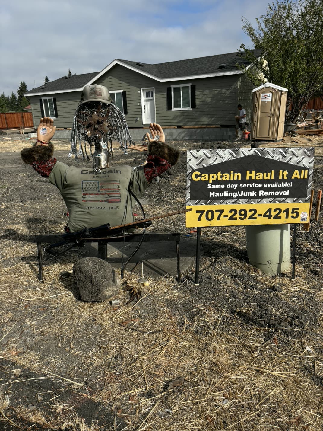 Scarecrow display positioned beside service sign on residential property.