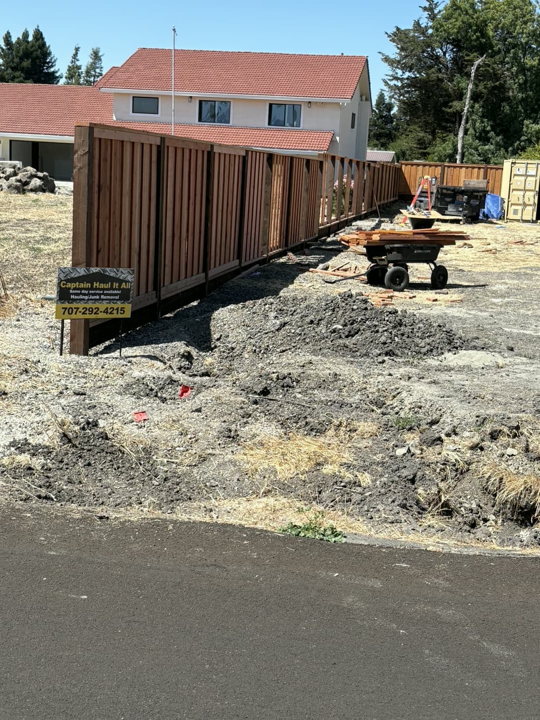 Leveled ground after hauling and cleanup work near wooden fence.